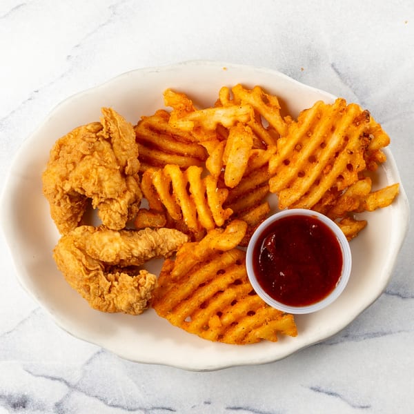 Crispy chicken tenders and seasoned waffle fries with a side of dipping sauce on a white plate.